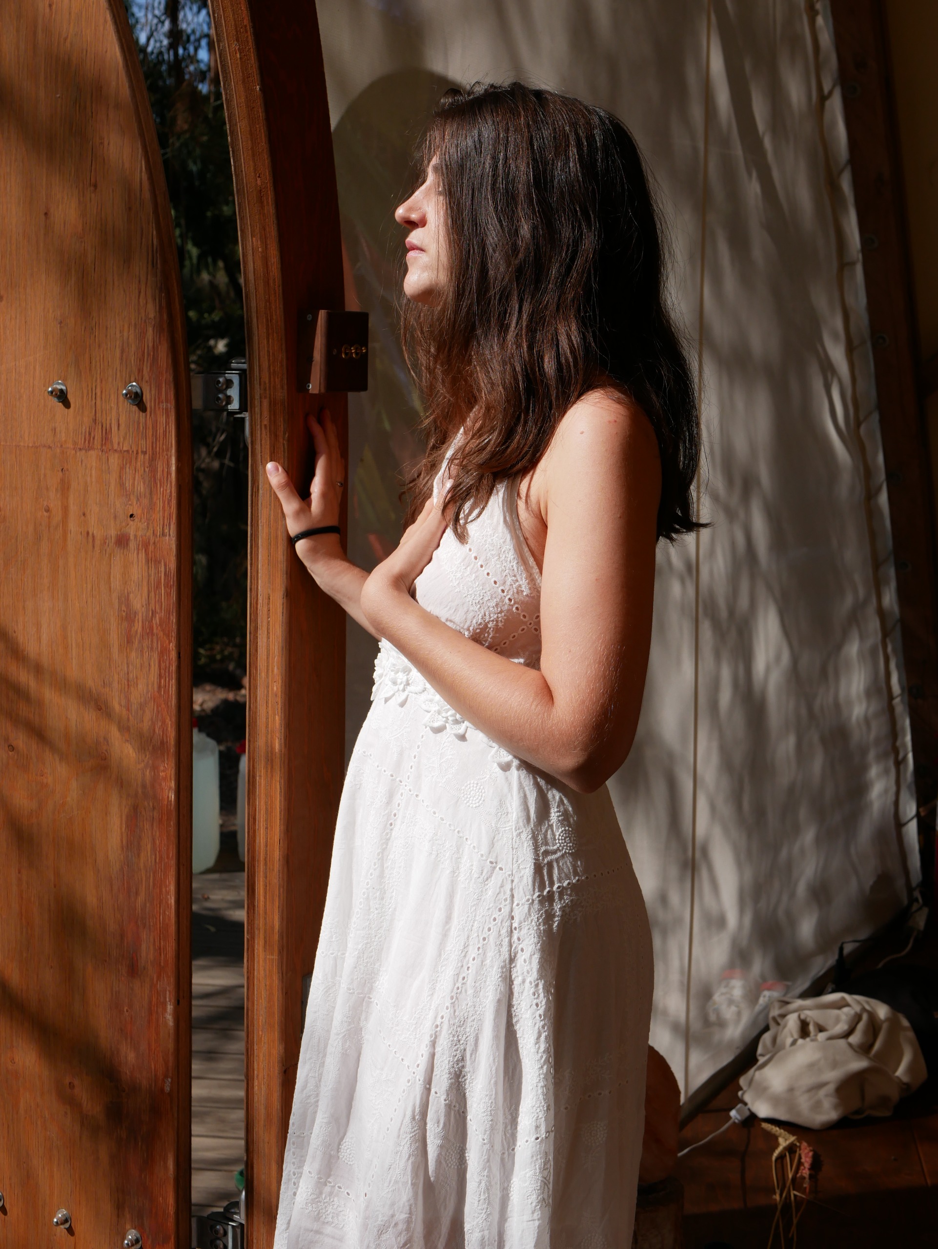 Agathe in contemplative stillness at a sunlit wooden doorway